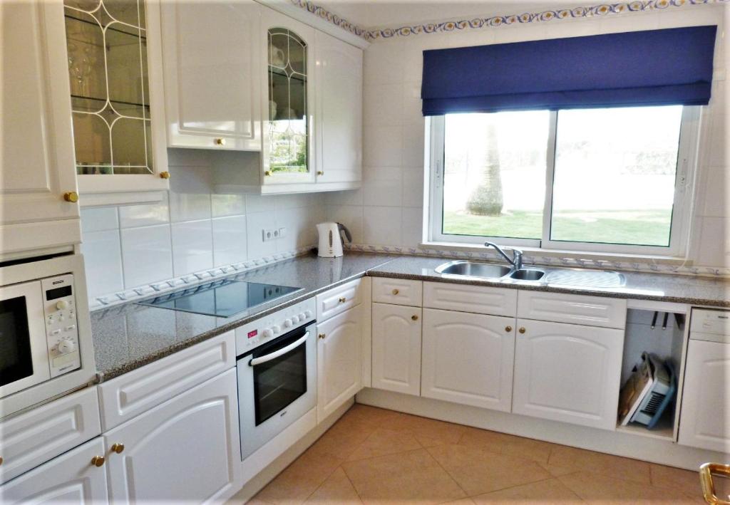 een keuken met witte kasten, een gootsteen en een raam bij Boavista 73 in Lagos