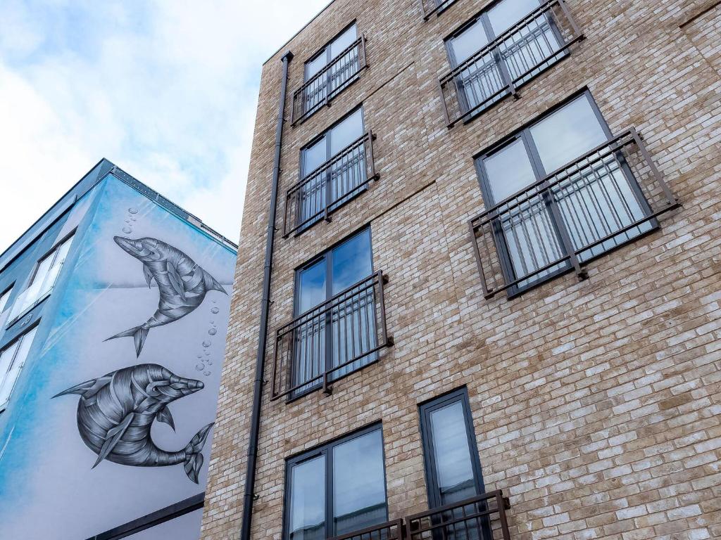 un edificio de ladrillo con un mural de delfines. en Luxurious Apartments Hackney near Train Station en Londres
