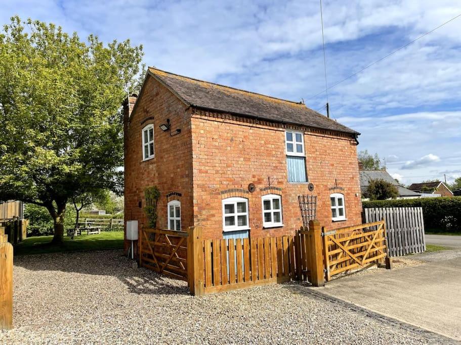 un piccolo edificio in mattoni rossi con cancello in legno di Cottage at The Butchers Arms a Gloucester