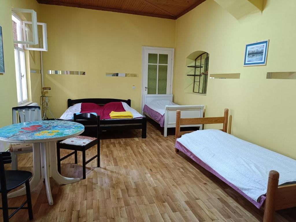 a room with two beds and a table and chairs at Micro Maxi House in Bela Crkva
