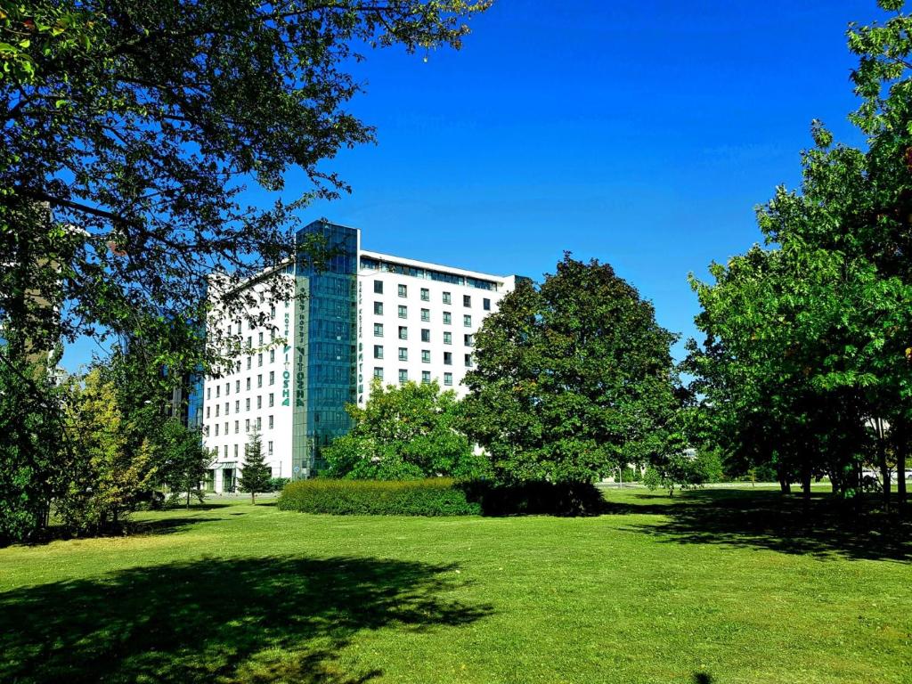 ein großes Gebäude mit einem grünen Feld davor in der Unterkunft Vitosha Park Hotel in Sofia