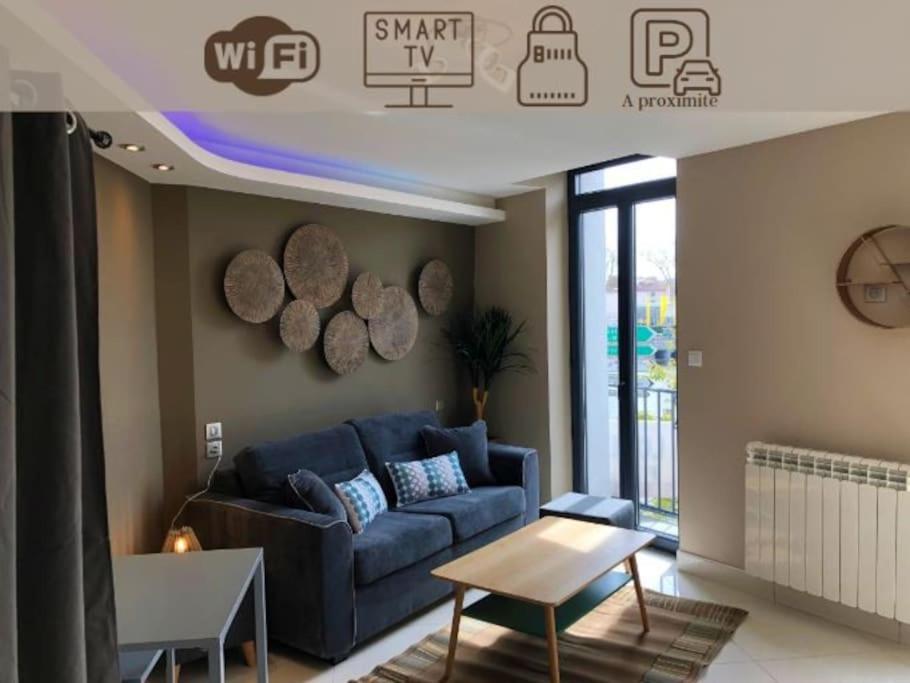 un salon avec un canapé bleu et une table dans l'établissement RDC 2 - Studio meublé centre-ville, au pied du pont Saint Pierre, à Montluçon