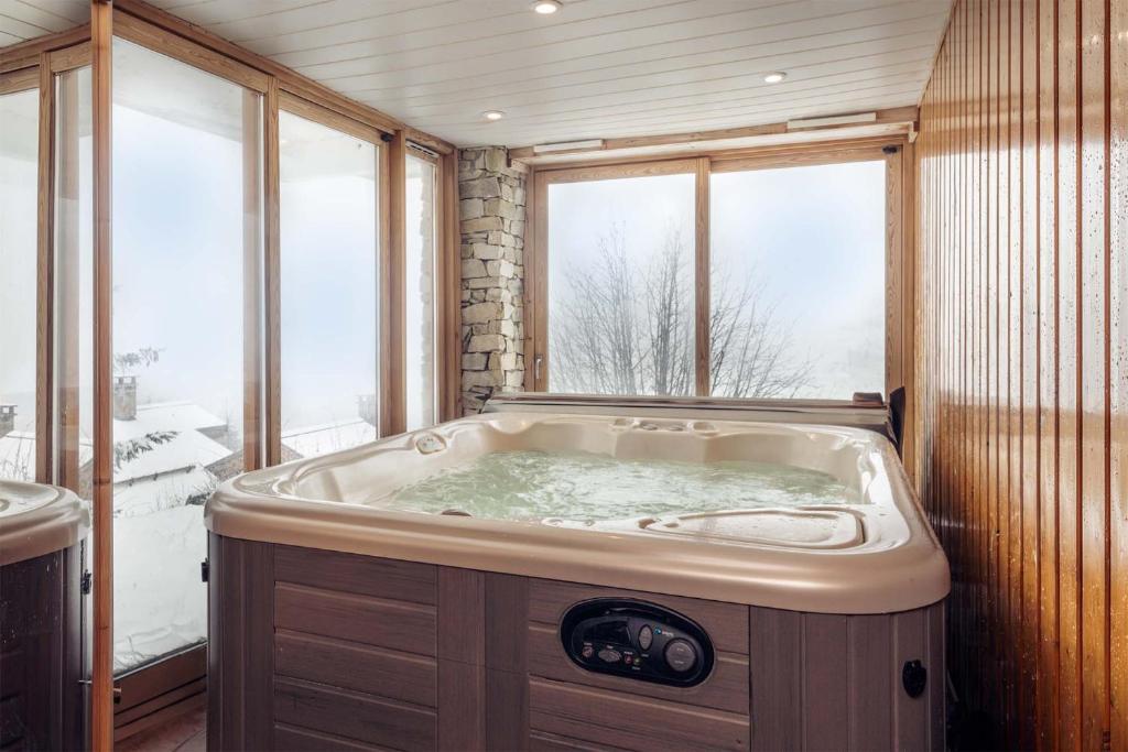 a large bath tub in a room with a window at Madame Vacances Chalet L'Arclusaz in Les Allues