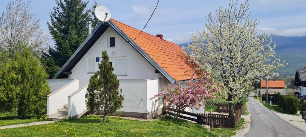 een wit huis met een oranje dak bij Apartment Mrsinj in Korenica