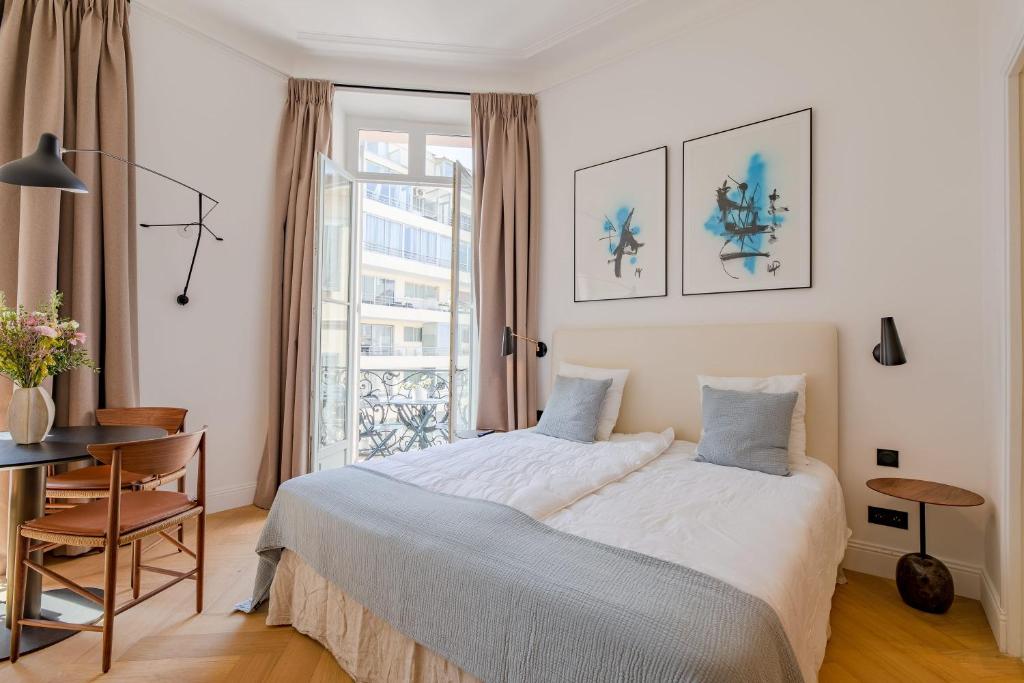une chambre avec un lit, une table et une fenêtre dans l'établissement La Guitare 23 - Large modern studio with balcony in center of Cannes, just behind Grand Hotel, à Cannes