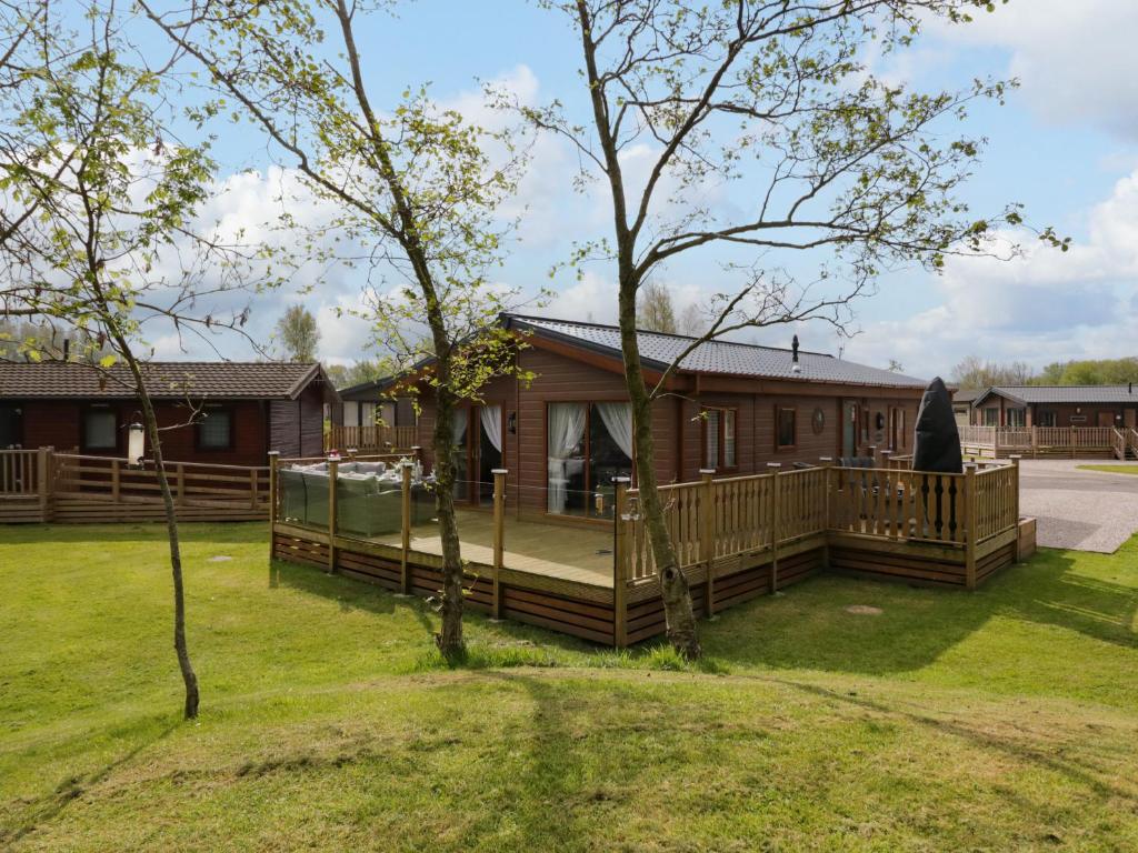 a log cabin with a deck and a house at Lakeland Dream South Lakeland Leisure Lodge in Carnforth