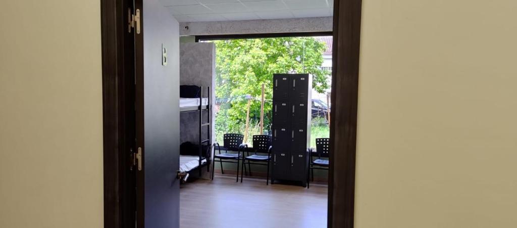 Una puerta a una habitación con balcón con sillas en Hostel Azul Cielo en O Pedrouzo