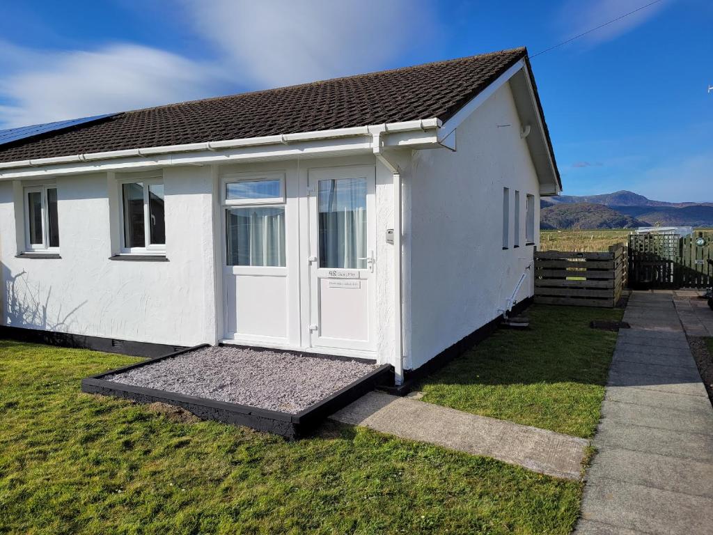 una pequeña casa blanca con una puerta blanca en 48 Glan Y Mor en Fairbourne