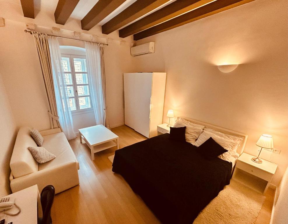 Un dormitorio con una cama negra y un sofá en una habitación en Rooms Klarisa Palace, en Dubrovnik