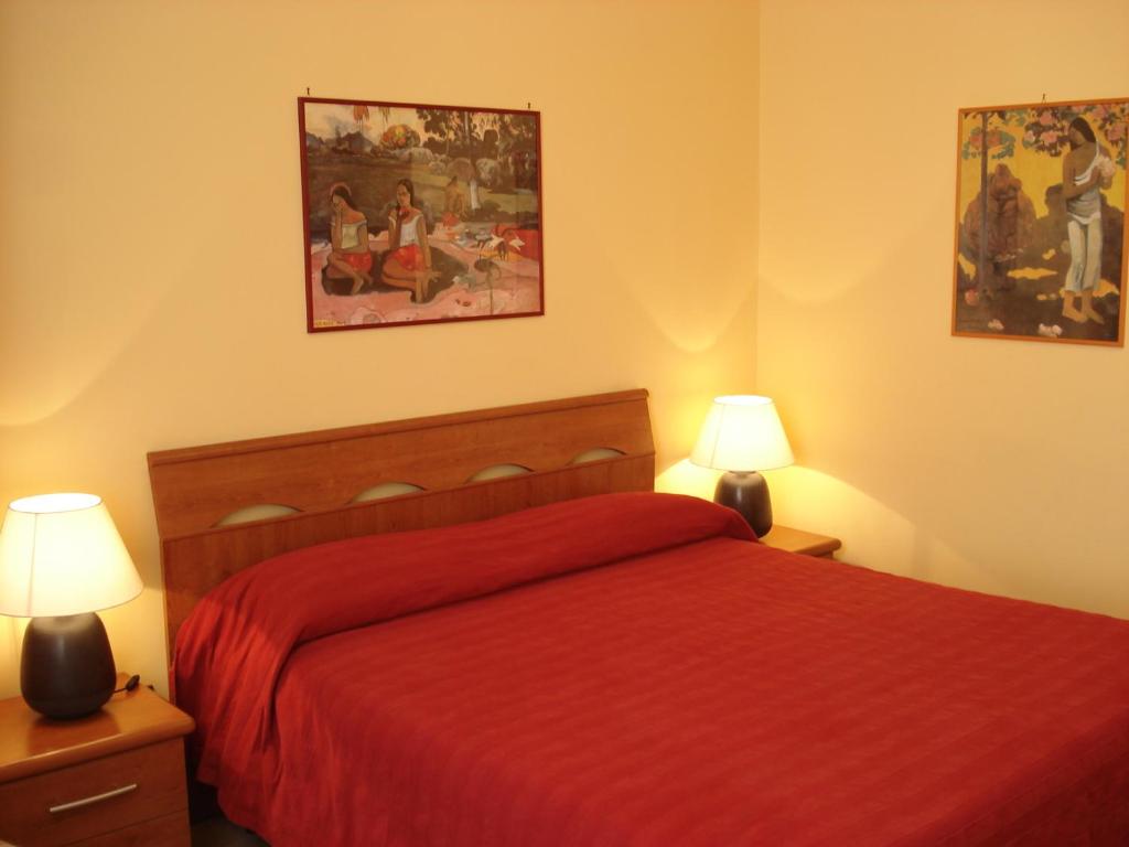 ローマにあるB&B La Bella Giulianaのベッドルーム1室(赤いベッド1台、ランプ2つ付)