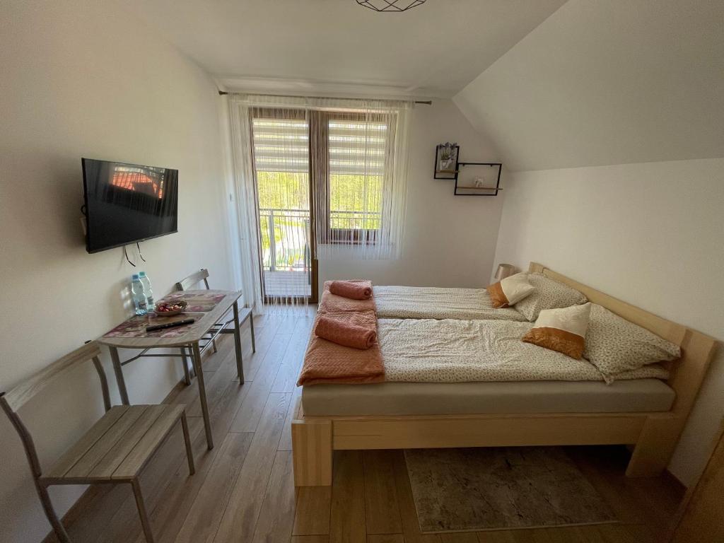 um quarto com uma cama, uma mesa e uma televisão em Apartament Rybical - POKOJE em Ryn