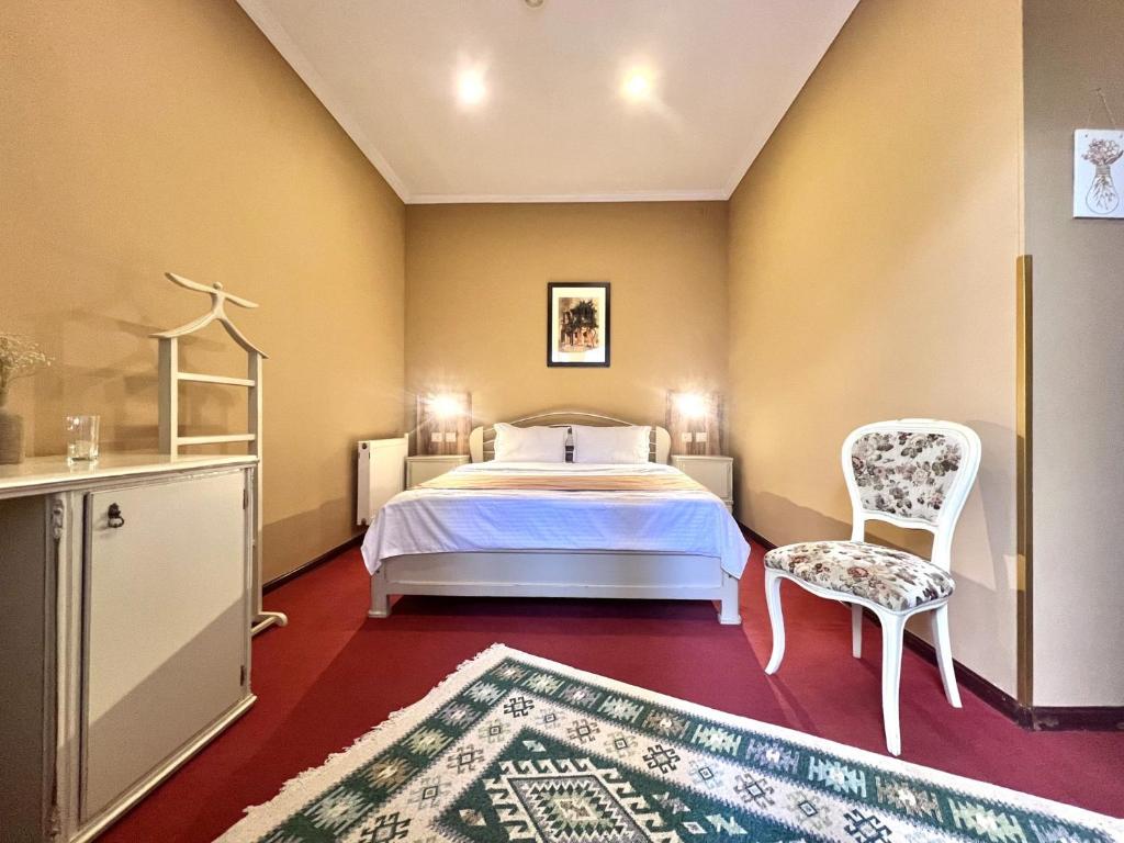 a bedroom with a bed and a chair and a rug at Madera Hotel in Tbilisi City