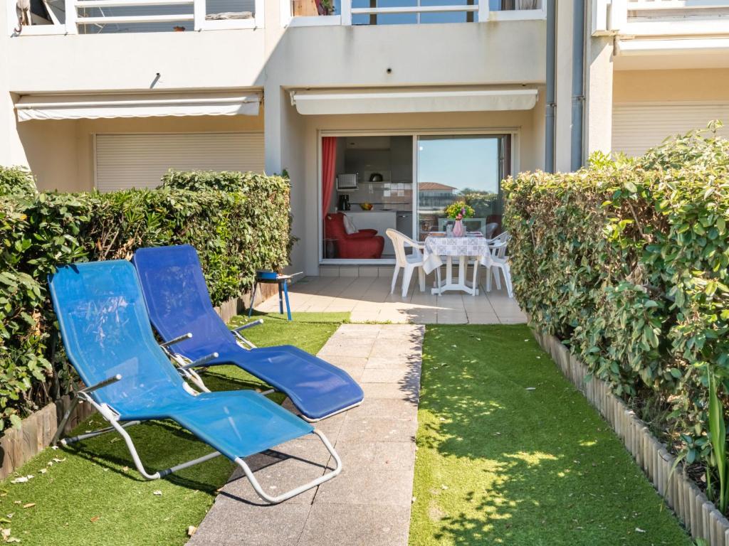 deux chaises bleues assises sur une pelouse devant une maison dans l'établissement Apartment Les Pêcheurs-4 by Interhome, à Mimizan-Plage