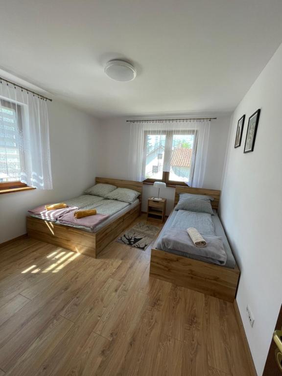 two beds in a room with wooden floors and windows at Apartament Rybical in Ryn