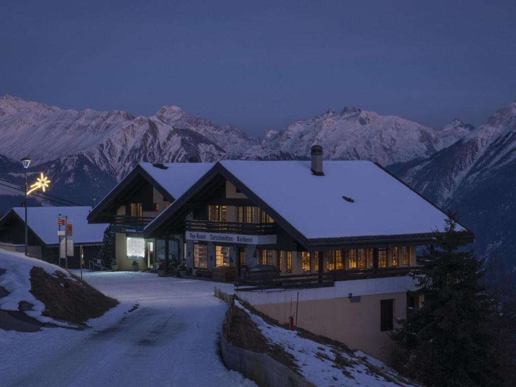 a house in the snow with mountains in the background at Apartment Appartementhaus Zurschmitten 16 by Interhome in Riederalp
