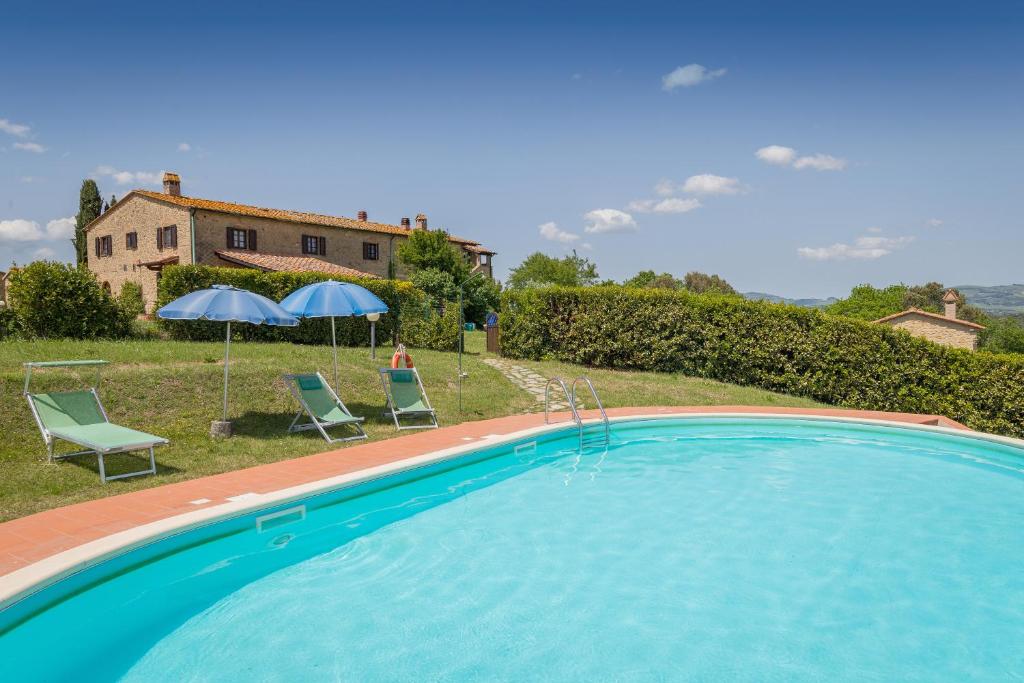 ein Pool mit zwei Stühlen und Sonnenschirmen sowie ein Haus in der Unterkunft Santa Lina - Alloro in Pomarance