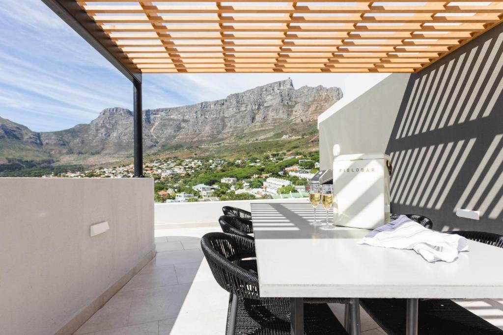 a kitchen with a table and chairs with mountains in the background at The View - Brand new Penthouse with private rooftop pool in Cape Town
