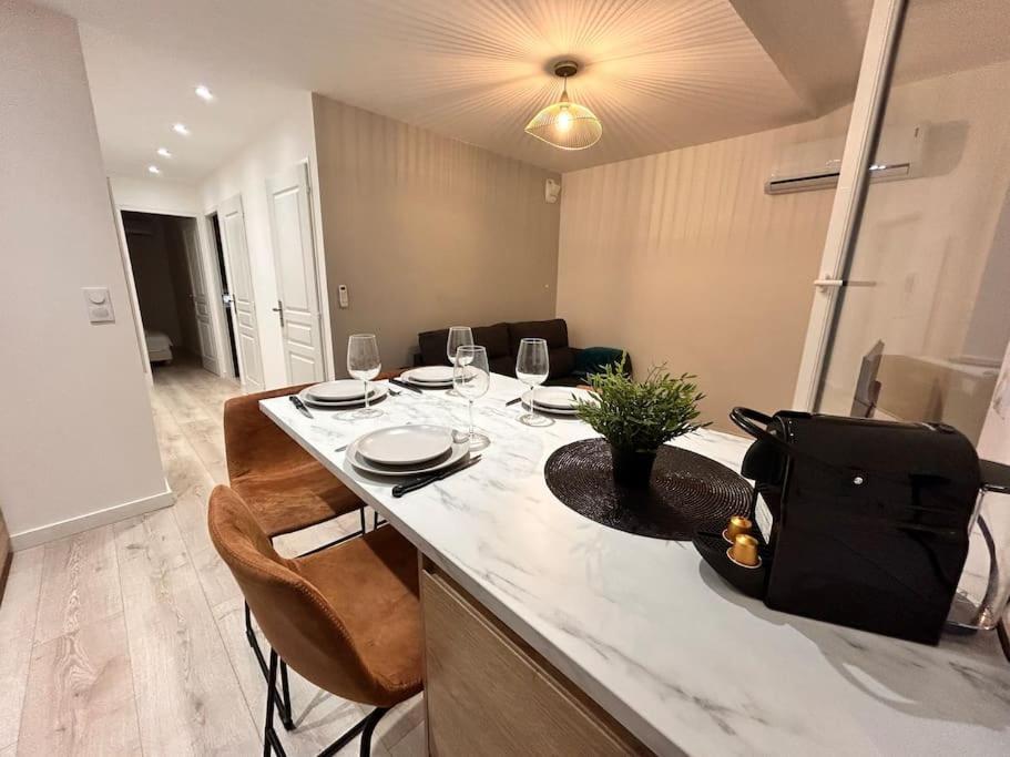 - une cuisine avec une table, des chaises et des verres à vin dans l'établissement Emma - 4/6 pers NEUF- Hyper centre Clim Terrasse, à Saint-Raphaël