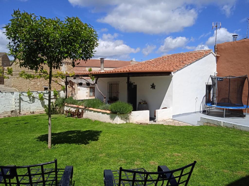 una pequeña casa blanca con un árbol en el patio en Casa Rural Cariño, en Armañanzas