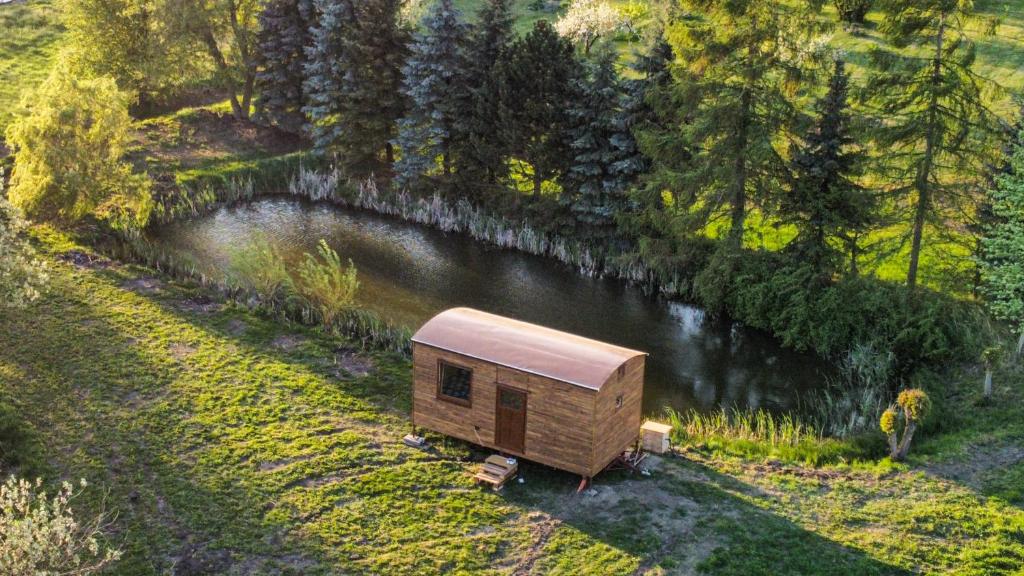 a small cabin next to a lake in a field at Maringotka na kraji rybníka 