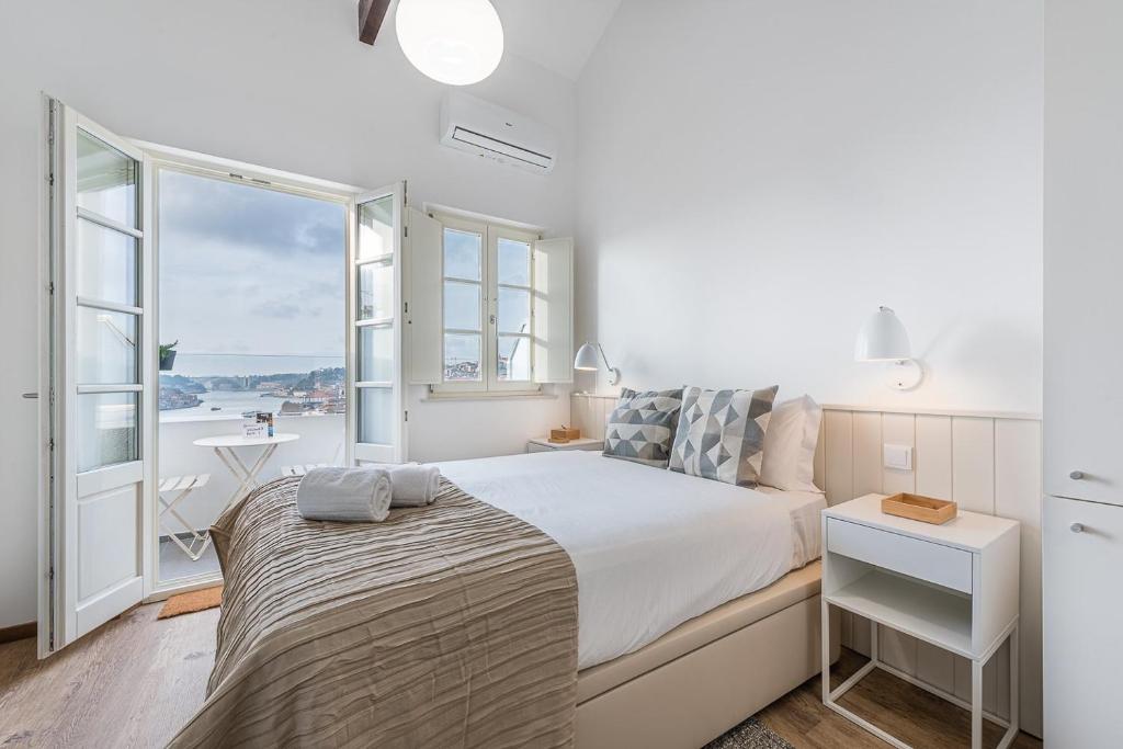 a white bedroom with a bed and a large window at GuestReady - Port Studio 2 in Bandeira