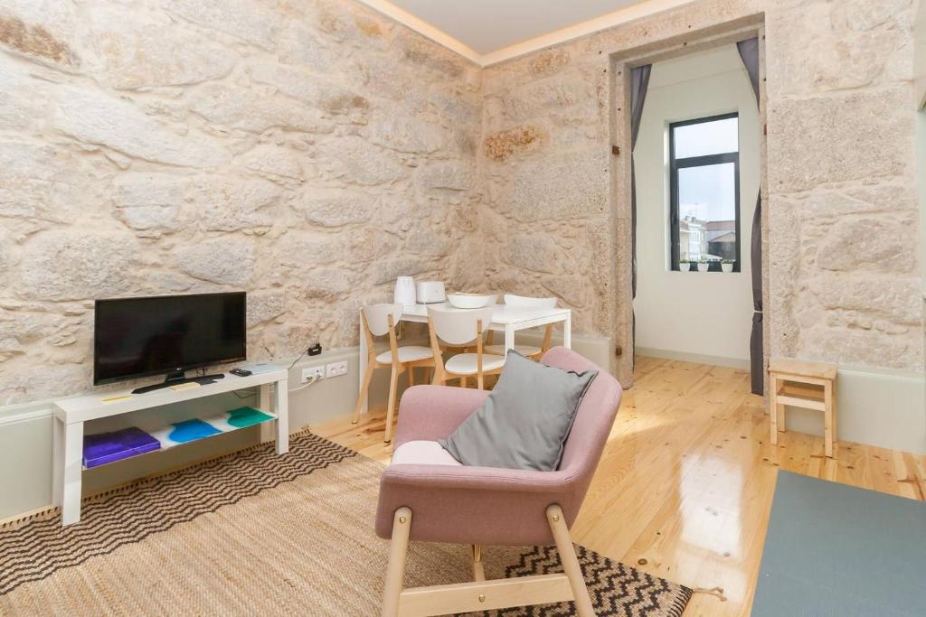 ein Wohnzimmer mit einem TV, einem Stuhl und einem Tisch in der Unterkunft GuestReady - Charming Downtown and Quiet Apartment in Porto