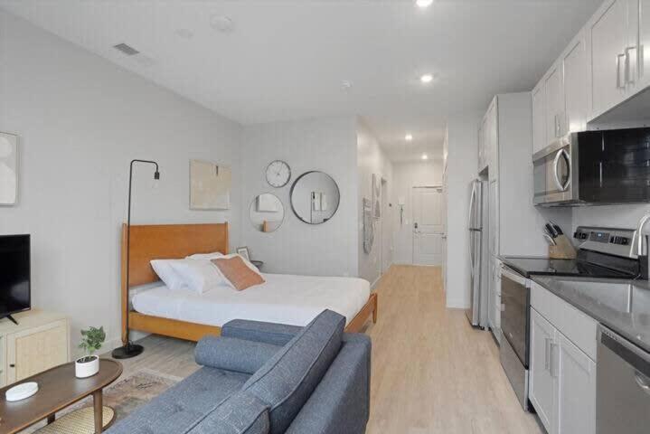 a room with a bed and a couch and a kitchen at CozySuites Spacious SDO, Lawrenceville in Pittsburgh