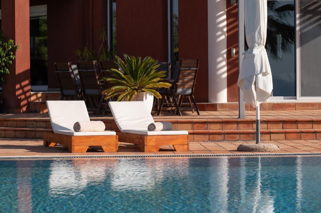 two chairs and an umbrella next to a swimming pool at 3 Palm Villa in Chalkida