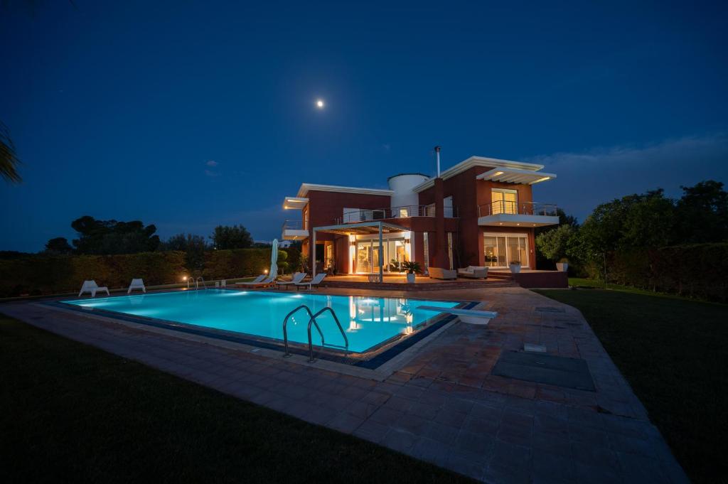 a house with a swimming pool at night at Palm 3 Villa in Chalkida
