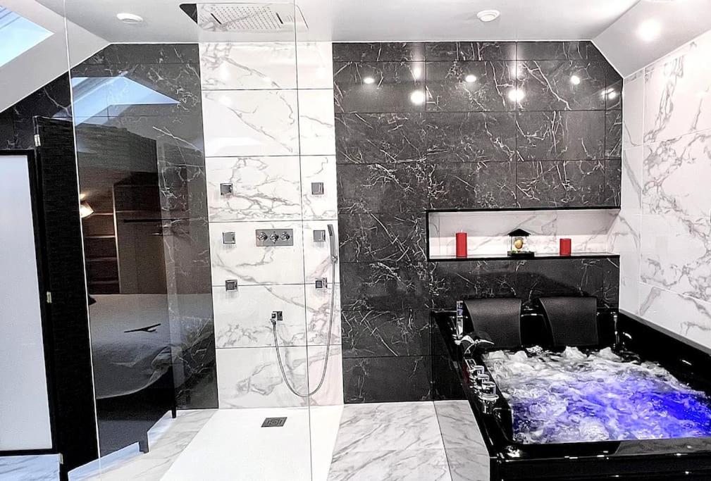 La salle de bains est pourvue d'une douche et d'un mur noir. dans l'établissement Loft Évasion luxe Jacuzzi, à Reims