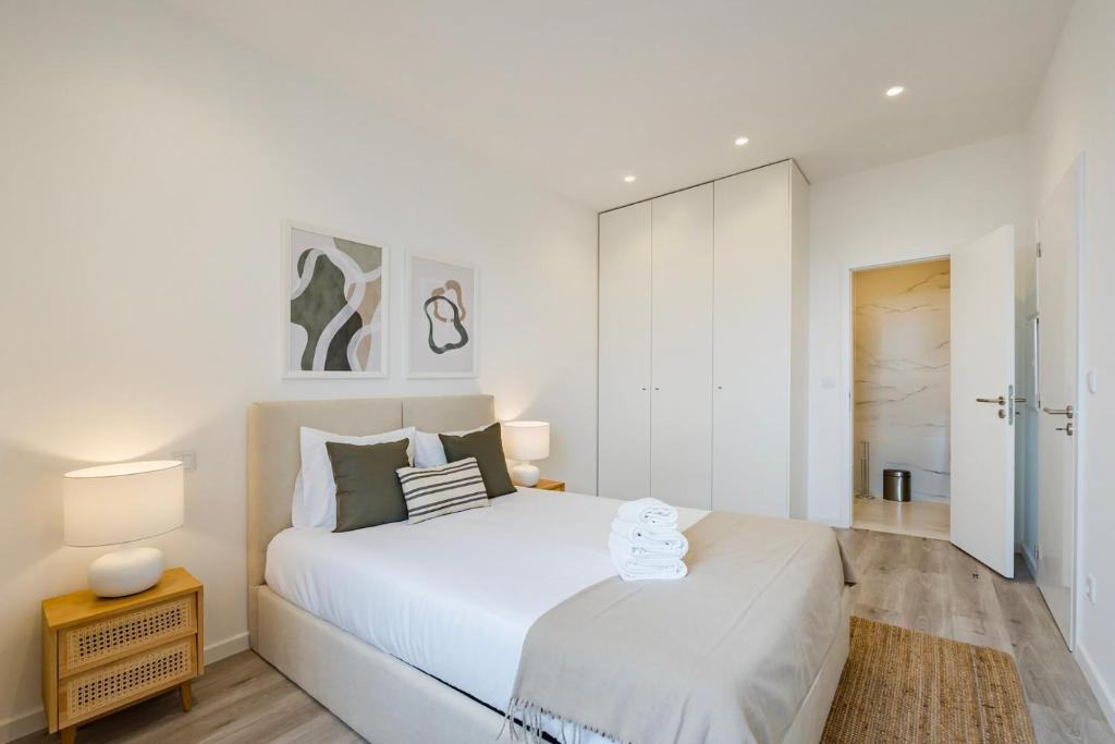- une chambre blanche avec un grand lit blanc et deux lampes dans l'établissement GuestReady - Cozy place in Matosinhos, à Matosinhos