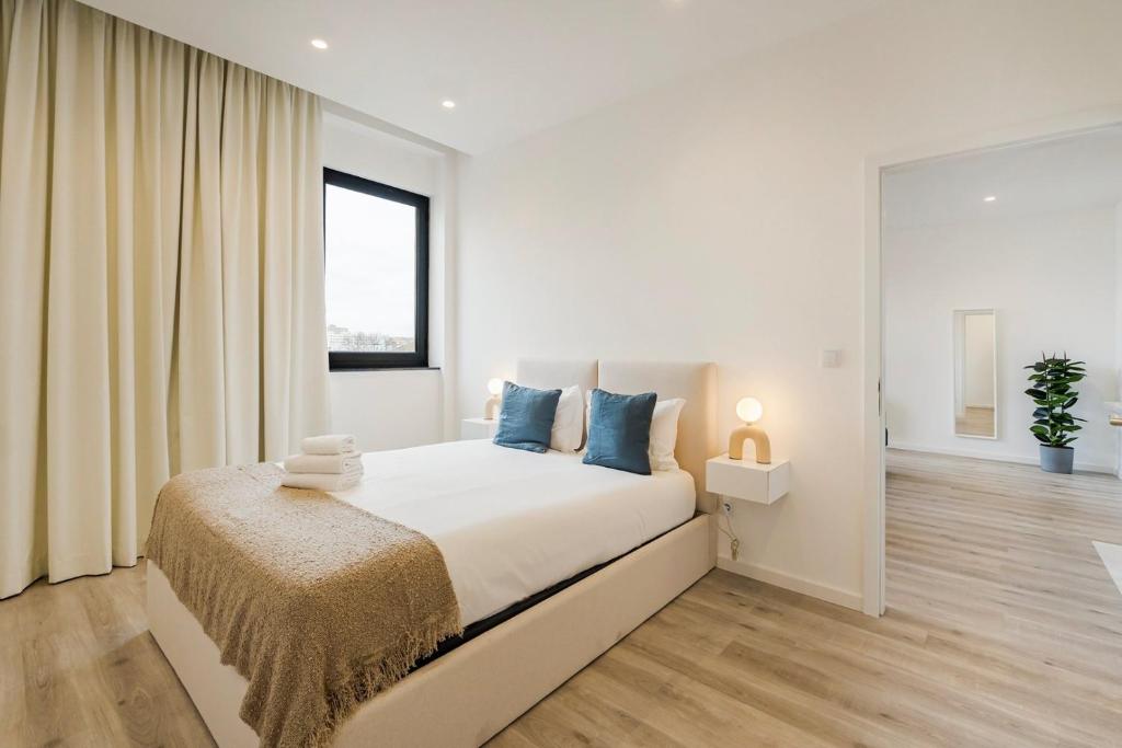 a white bedroom with a large bed with blue pillows at GuestReady - Matosinhos Deluxe near the beach in Matosinhos