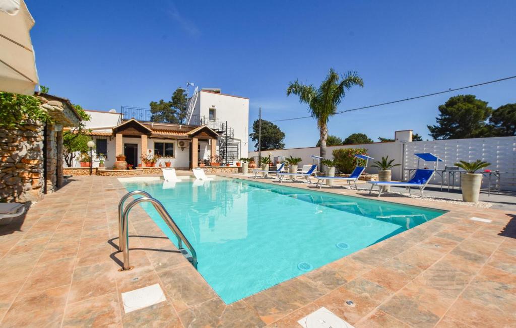 Stunning Home In Terrasini With Private Swimming Pool, Can Be Inside Or Outside في تيراسيني: مسبح والكراسي الزرقاء والبيت