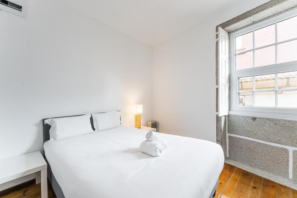 un letto bianco in una stanza con finestra di GuestReady - Modern Duplex, Neo-Classical Building a Porto