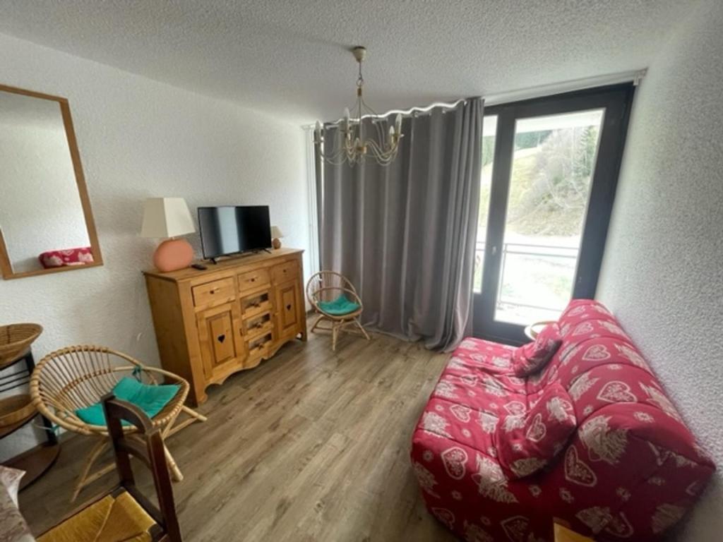 a living room with a red couch and a window at Appartement Les Adrets-Prapoutel, 2 pièces, 5 personnes - FR-1-557-105 in Les Adrets