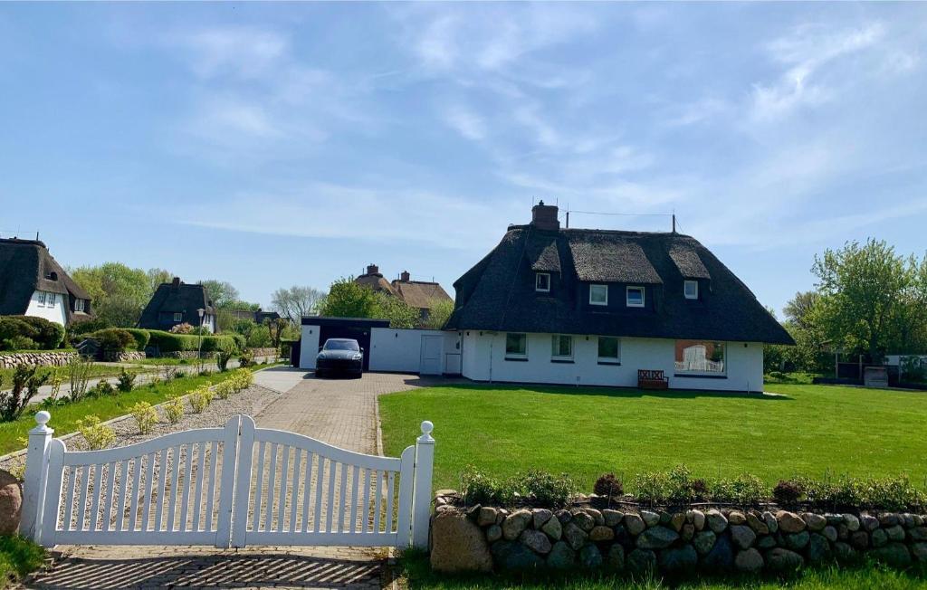 a white house with a thatched roof and a driveway at Landhus-Sylt in Archsum