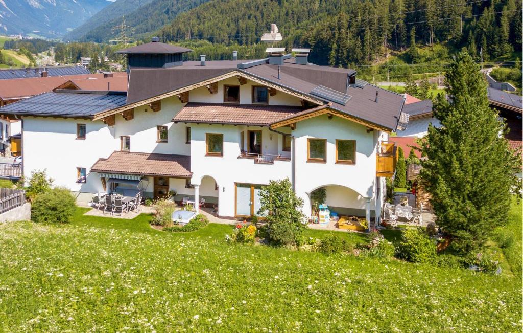 a large white house on top of a green field at 2 Bedroom Awesome Apartment In St, Anton in Sankt Anton am Arlberg