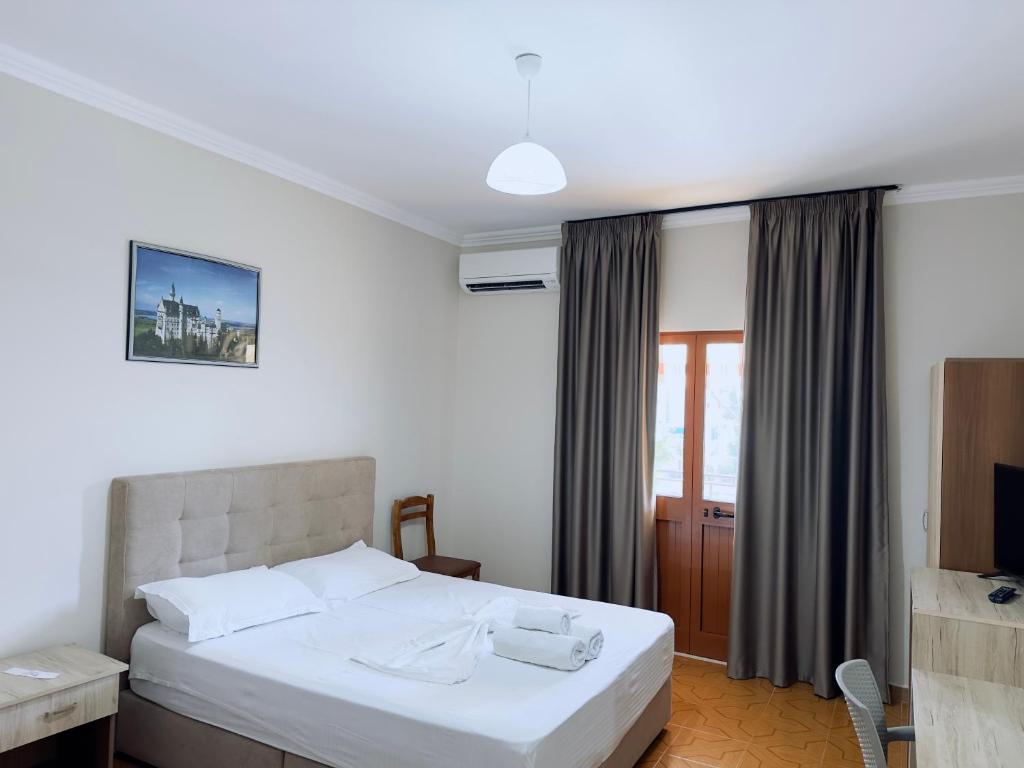1 dormitorio con 1 cama blanca y TV en Molla Hotel Restorant en Shëngjin