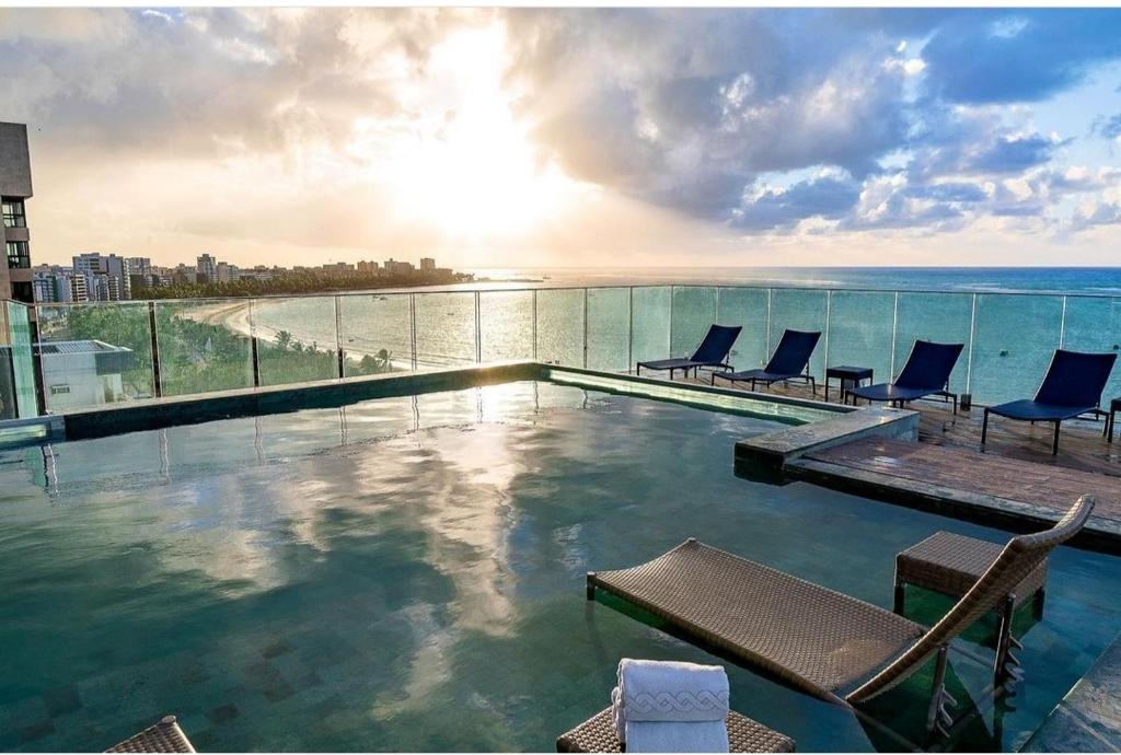 a swimming pool with chairs and a view of the ocean at PAJUCARA FRONT BEACH 2 in Maceió