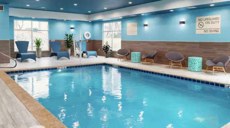 una piscina en una habitación de hotel con paredes y sillas azules en Hampton Inn St Ignace Lakefront Mackinac en Evergreen Shores