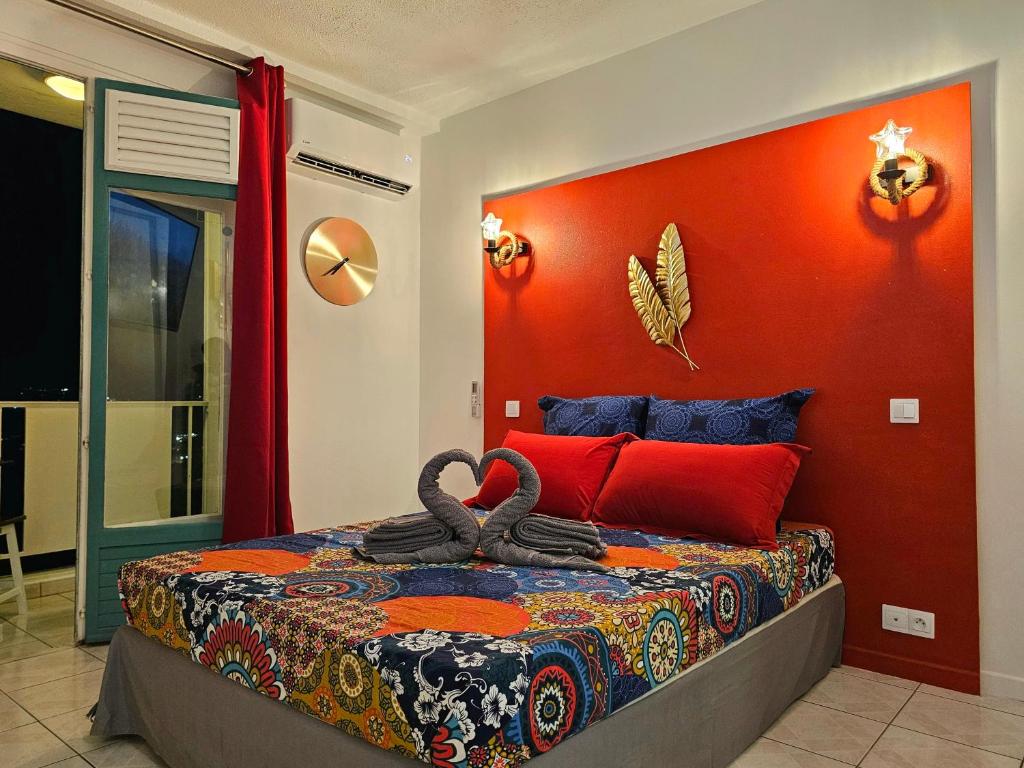 een slaapkamer met een bed met een oranje muur bij Sweet Crépuscule - Studio avec Vue Mer Imprenable & Piscine in Les Trois-Îlets