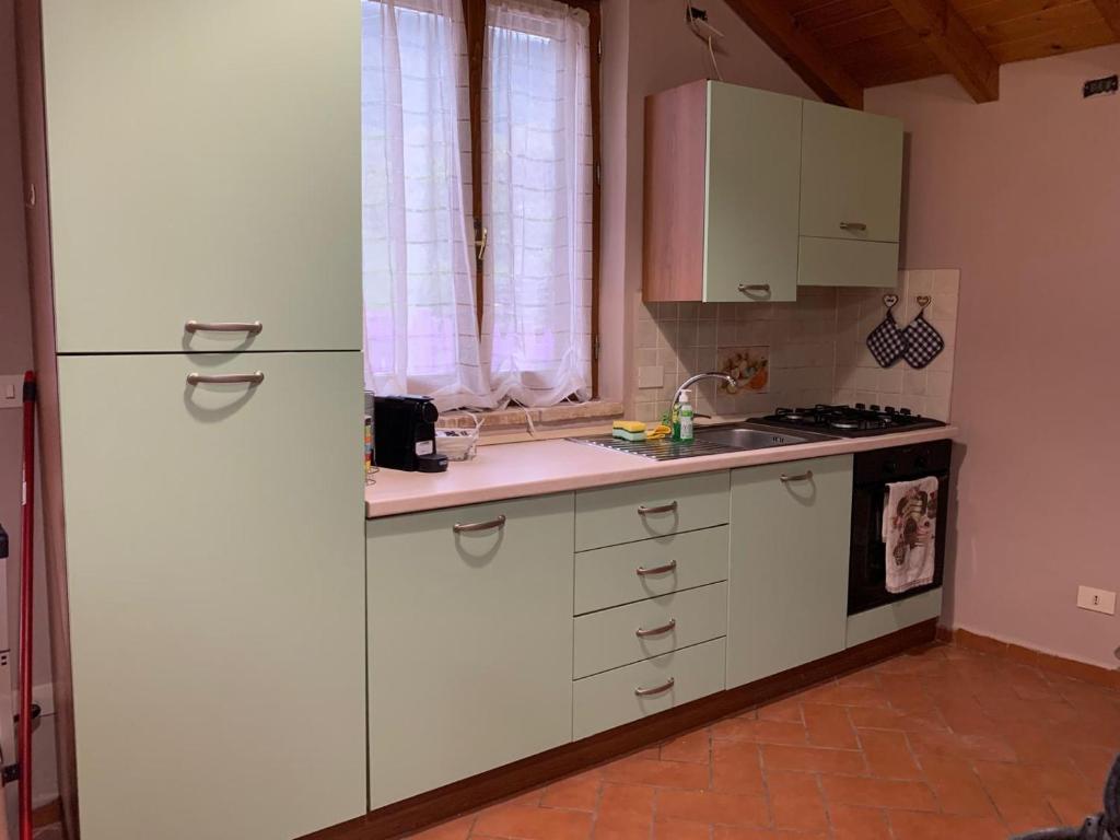 eine Küche mit weißen Schränken und einem Kühlschrank in der Unterkunft Casetta Ai Fiassoni in Parma