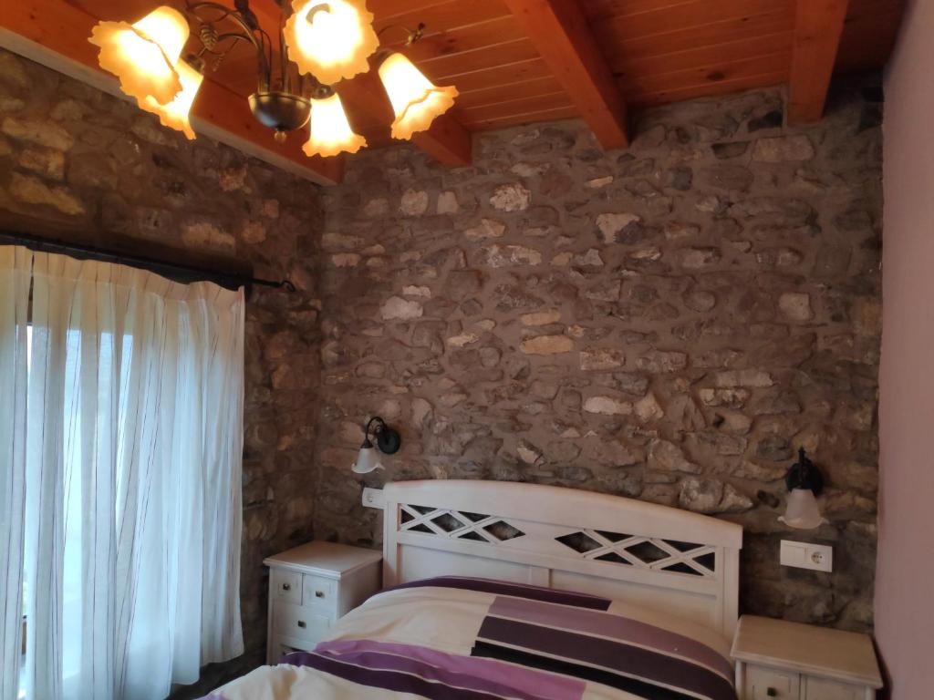 a bedroom with a bed and a stone wall at CASA TOMASIN 