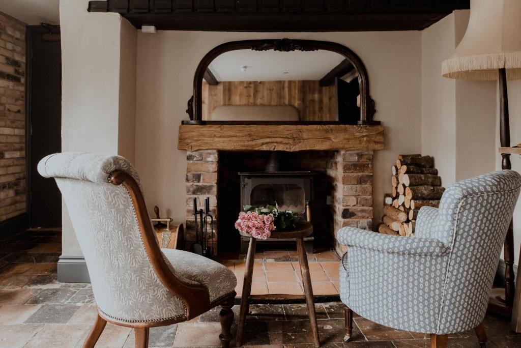 a living room with two chairs and a fireplace at The Fitz Farmhouse in Swynnerton