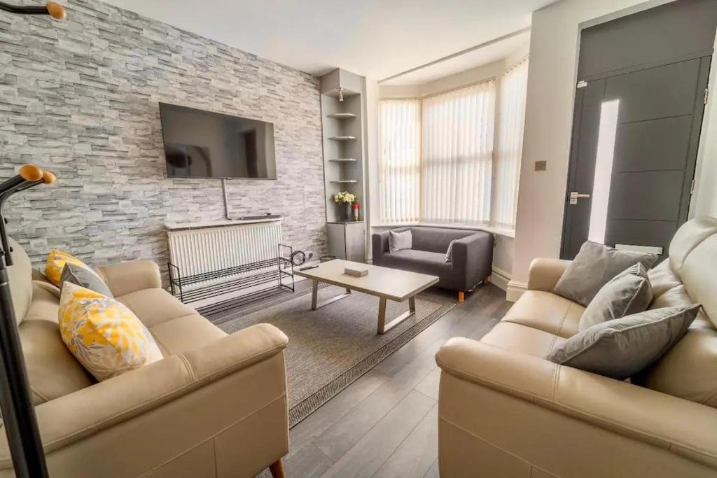 a living room with two couches and a stone wall at Pass the Keys Stylish 5 bed near major companies in Nottingham