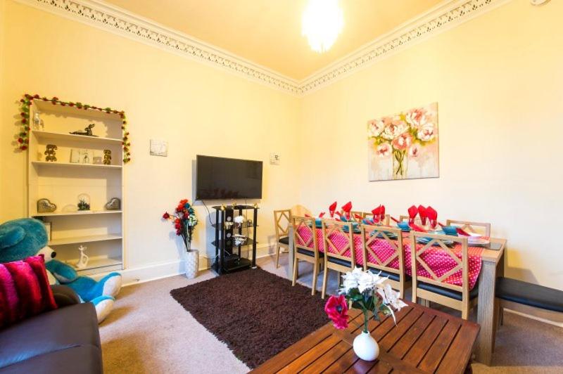sala de estar con sillas rosas y TV en Edinburgh Morrison Central ApartHotel, en Edimburgo
