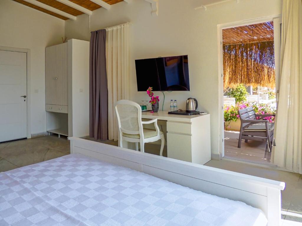 a room with a bed and a desk with a television at Oza Boutique hotel in Gümüşlük