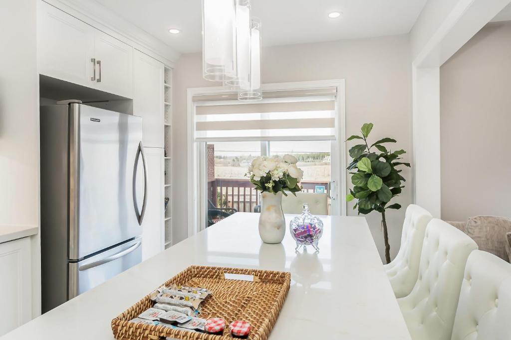 uma cozinha branca com uma mesa e um frigorífico branco em Pristine Pet & Smoke Free 4-Bedroom home near Canada's Wonderland em Vaughan