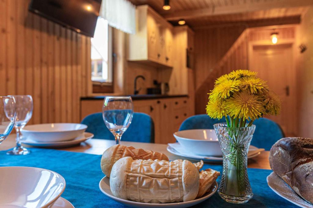 een tafel met een bord brood en een vaas met bloemen bij Apartament GóralSki z widokiem na tatry in Brzegi