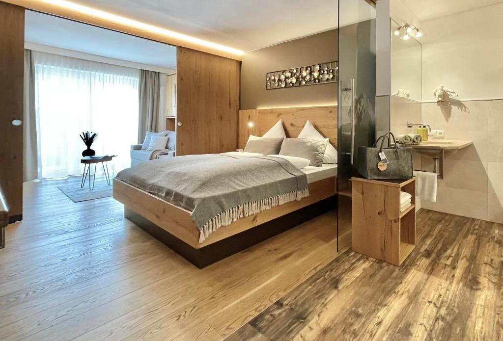 um quarto com uma cama grande e uma parede de vidro em moser-HOCHKÖNIG Genuss Wirtshaus Hotel em Maria Alm am Steinernen Meer